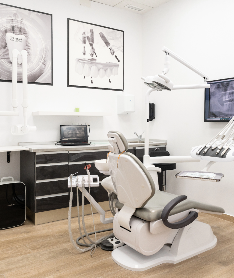 Consulta dental con silla, instrumentos y pantallas en un ambiente moderno y limpio.