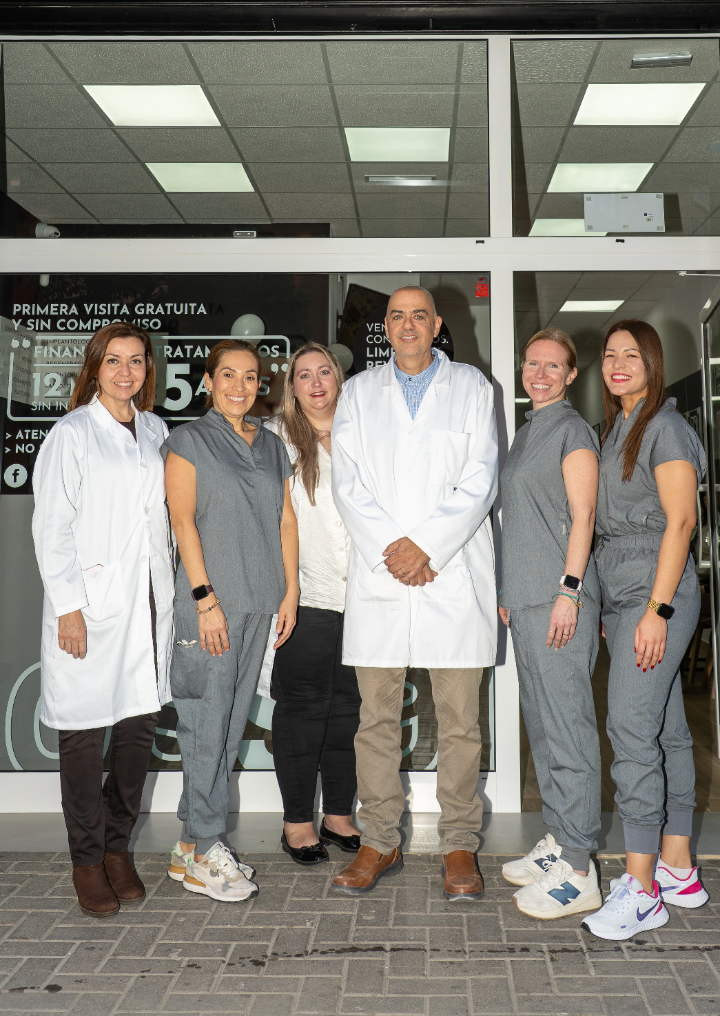 Grupo de profesionales sonrientes frente a la clínica dental Tossal Dental.